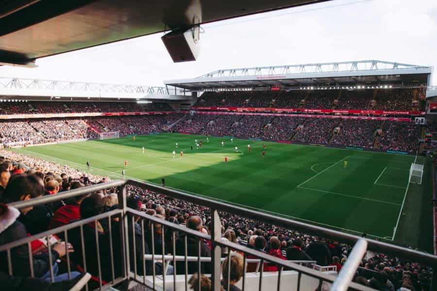 A crowd of spectators watches a football match in a stadium.