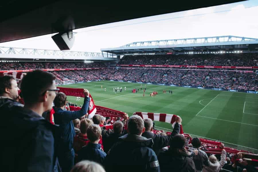 A crowd of Liverpool football fans watching a game at a stadium.