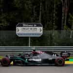 A Mercedes F1 car passes a Circuit De Spa road-sign at high speed.