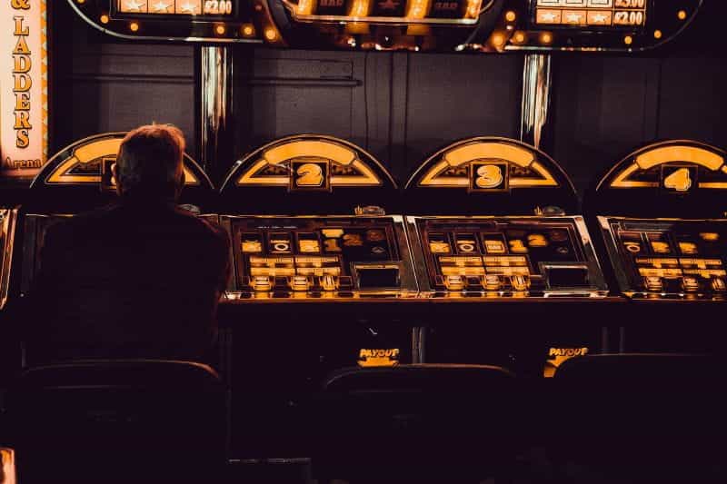 A man plays alone sitting at a row of machines.
