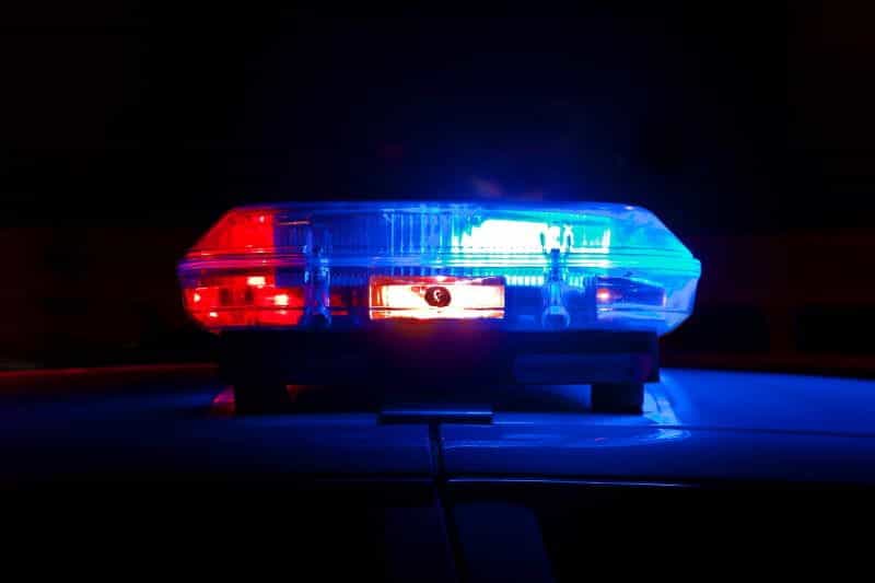 A police car light in right and blue shines on top of a car.
