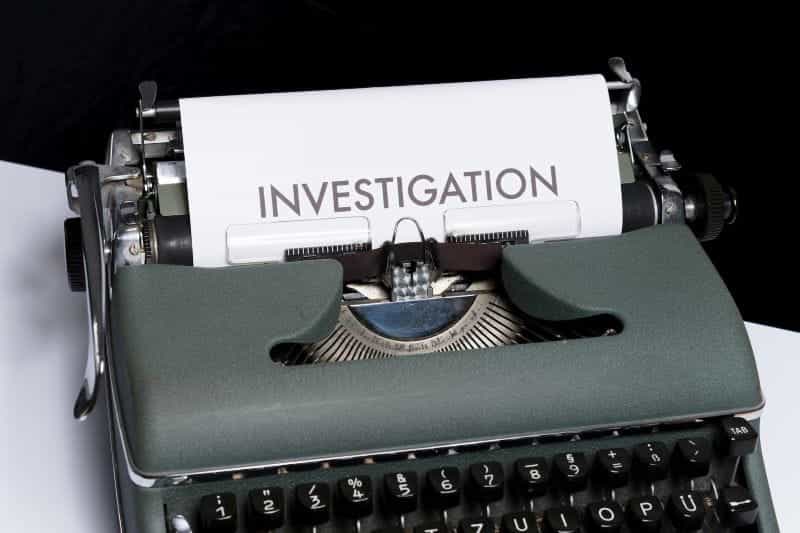 A typewriter has a paper jutting out of it with the word INVESTIGATION at the top.