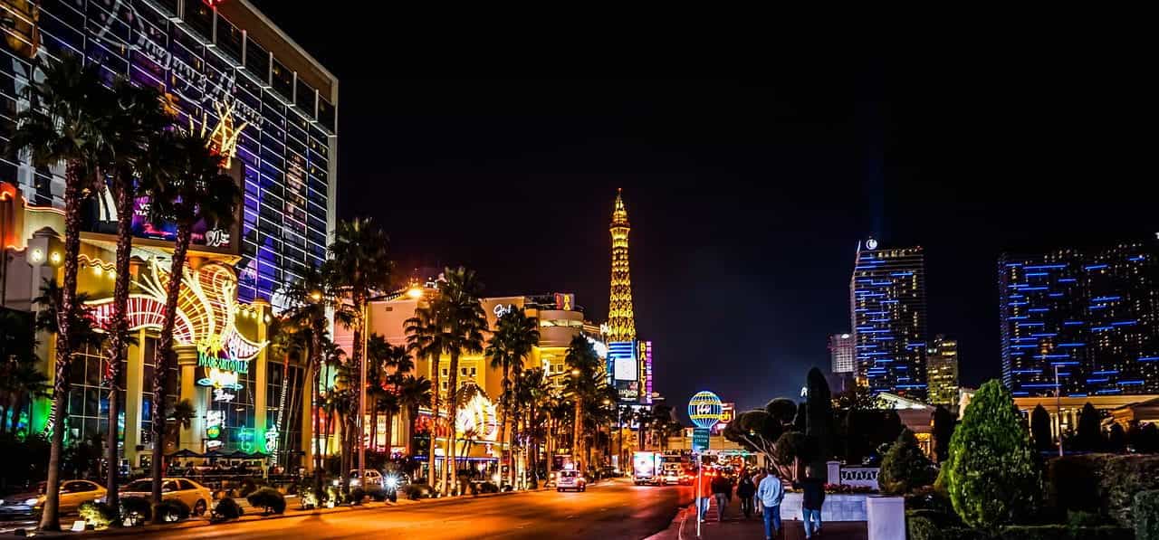 The world famous “strip” in downtown Las Vegas, Nevada, featuring a rich array of lit-up casinos, hotels, restaurants, storefronts, and the iconic replica Eiffel Tower in the back.