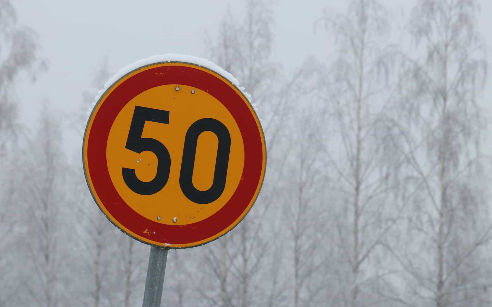 A traffic road sign displays the number 50 in a red and yellow circle.