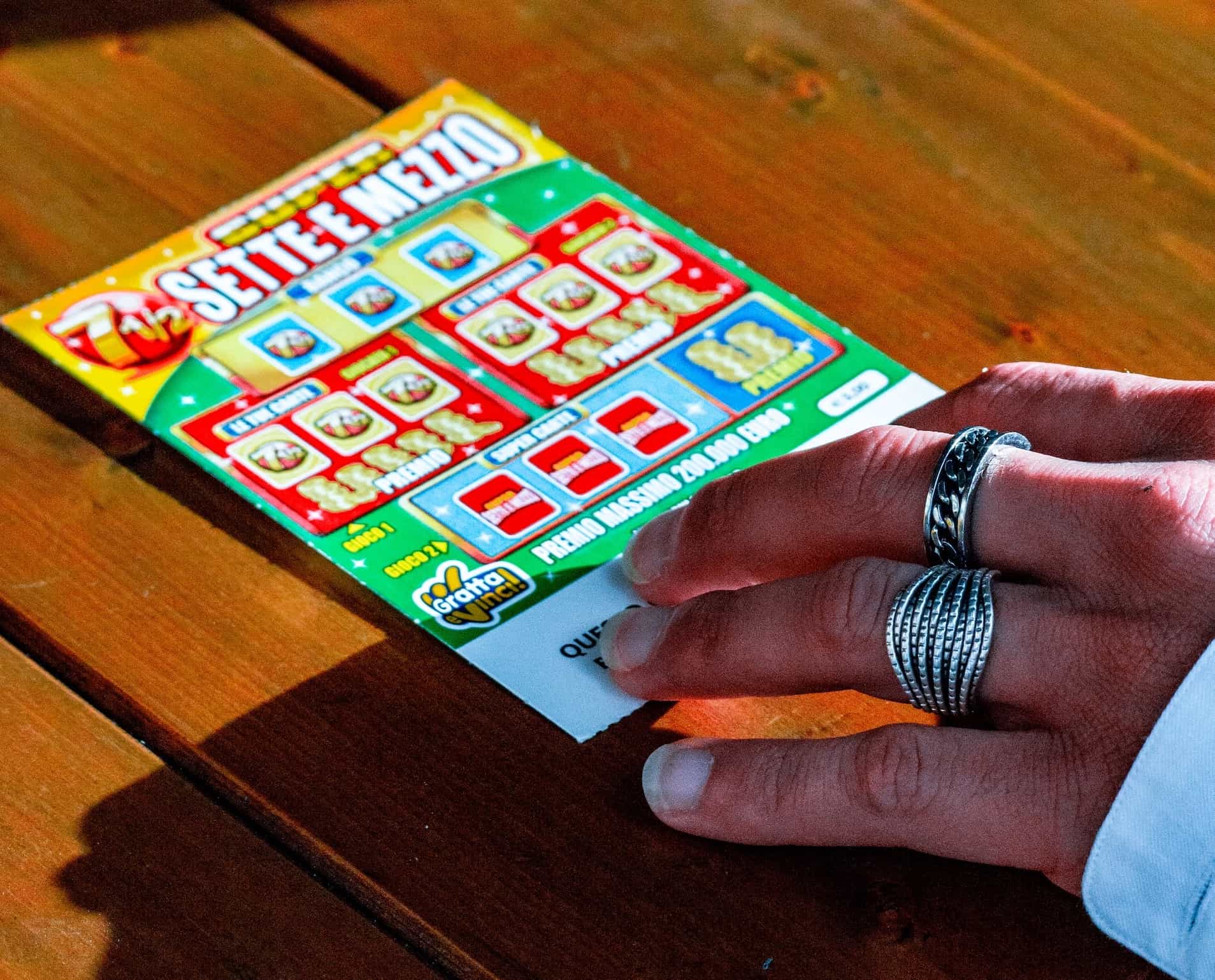 A hand with many silver rings touched a lottery ticket.